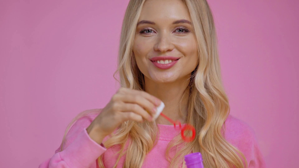smiling woman blowing soap bubbles isolated on pink - Footage, Video