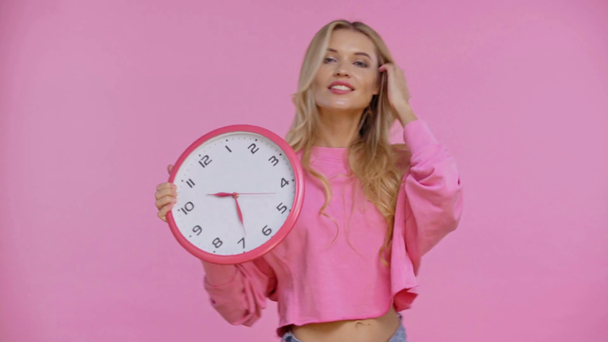 woman holding and pointing with finger at clock isolated on pink - Materiaali, video