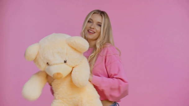 Lächelnde Frau tanzt mit Teddybär auf rosa - Filmmaterial, Video