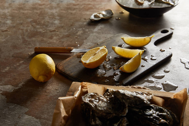 enfoque selectivo de ostras en cáscara cerca de derretir el hielo en la tabla de cortar
  - Foto, imagen