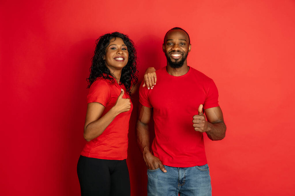 Young emotional african-american man and woman on red background - Foto, imagen