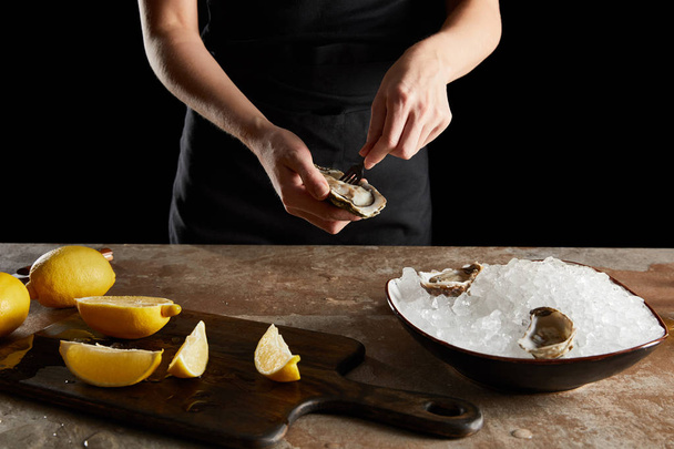 cropped view of woman holding fork near oyster isolated on black  - Foto, imagen