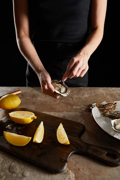 vista recortada del chef sosteniendo tenedor cerca de ostra fresca aislada en negro
  - Foto, Imagen