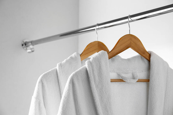 Soft comfortable bathrobes hanging on rack in closet - Foto, immagini