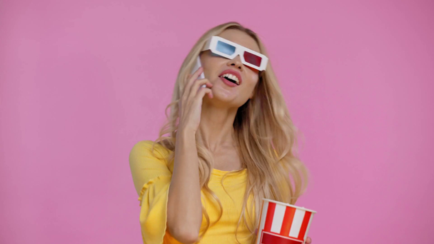 vrouw het eten van popcorn en praten op smartphone geïsoleerd op roze - Video