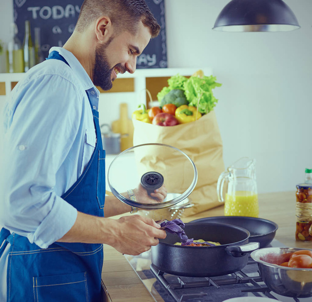 Lächelnder und selbstbewusster Koch steht in großer Küche - Foto, Bild
