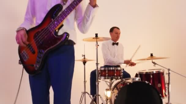 Musiikkibändi neljä ihmistä kirkkaissa vaatteissa soi kappaleen valoisa studio - kuvaamisen musiikkivideo
 - Materiaali, video