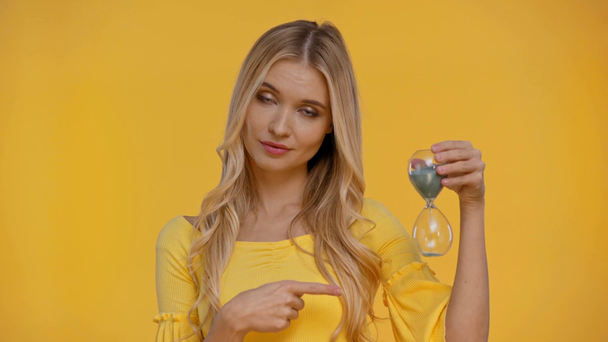 kobieta wskazująca palcem na klepsydrę odizolowaną w kolorze żółtym  - Materiał filmowy, wideo