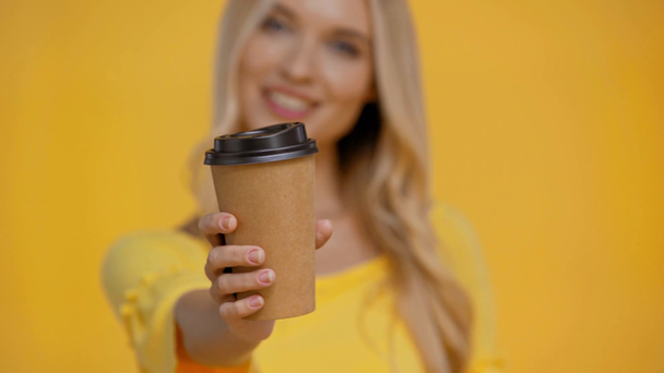 glimlachende vrouw houden wegwerpbeker geïsoleerd in geel - Video