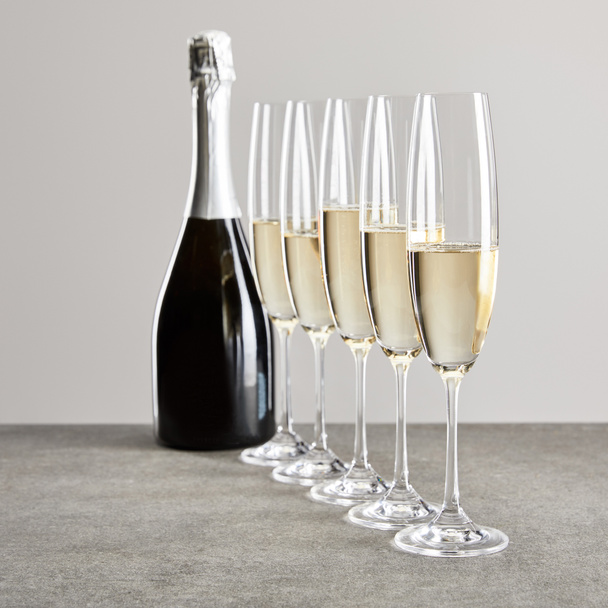 enfoque selectivo de copas de champán con vino espumoso cerca de botella aislado en gris
  - Foto, Imagen