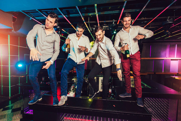 Mosolygó férfi barátok csoportja szórakozás az éjszakai klubban  - Fotó, kép