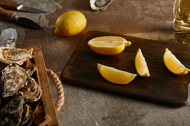 selective focus of delicious oysters in shells near lemons on wooden cutting board - Photo, Image