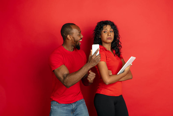 Young emotional african-american man and woman on red background - Foto, Imagen