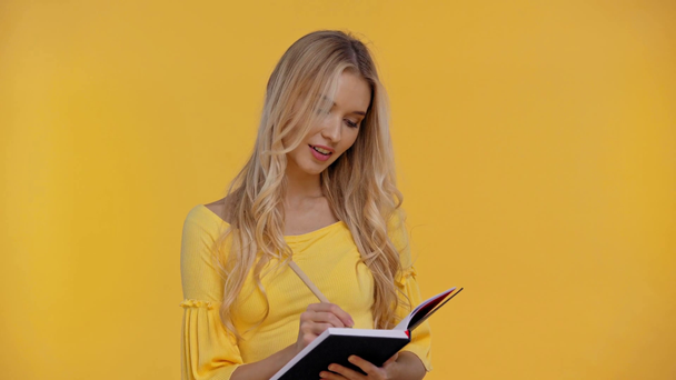 mosolygó nő írás notebook izolált sárga - Felvétel, videó