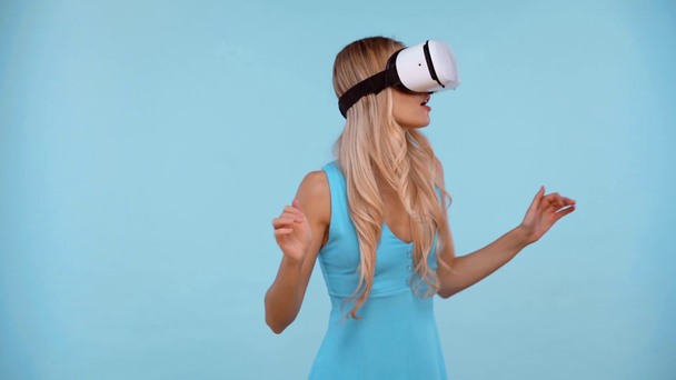 σοκαρισμένη γυναίκα με ακουστικά εικονικής πραγματικότητας απομονωμένα σε μπλε - Πλάνα, βίντεο