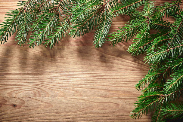 Cartão de Natal com galhos de árvore no fundo de madeira
 - Foto, Imagem