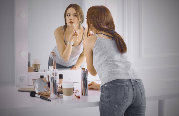 Mulher nova incrível fazendo sua maquiagem na frente do espelho. Portra
 - Foto, Imagem