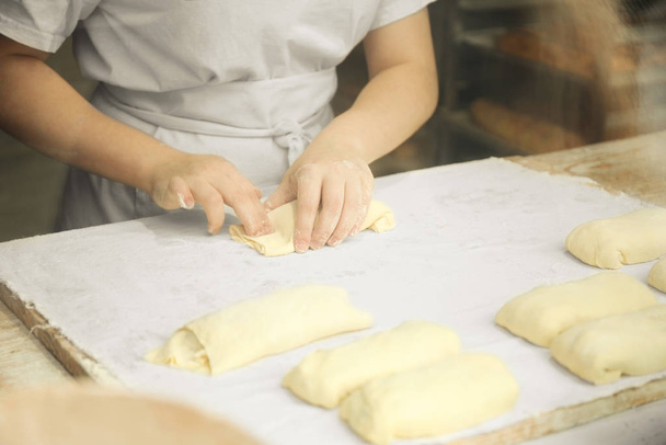 Professional chef rolling dough in the kitchen. Commercial baker - Foto, afbeelding