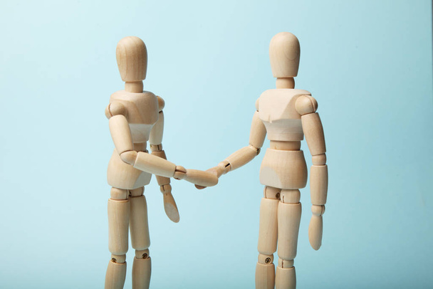 Two wooden figures of man shake hands. - Foto, imagen