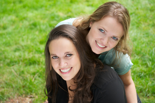 Портрет двух красивых девушек, улыбающихся на открытом воздухе
 - Фото, изображение