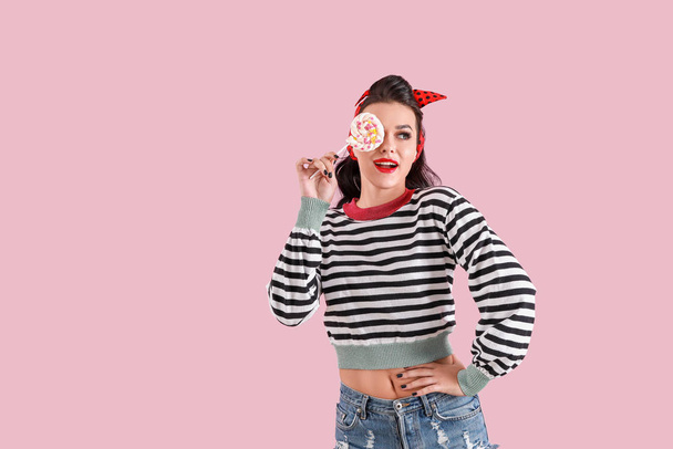 Portret van een mooie pin-up vrouw met lolly op kleur achtergrond - Foto, afbeelding