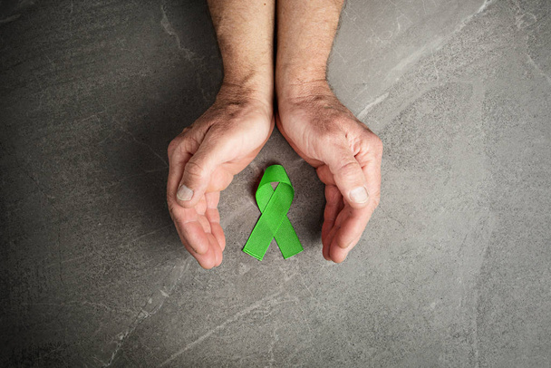 handen met groen lint, lymfoom kanker - Foto, afbeelding