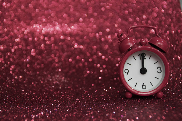 Pink clock to the right of the photo. Midnight on a pink background with a glitter  where you can write your message. Negative space. Copy space for advertising. Copy space area for text. Happy New Year - Photo, Image