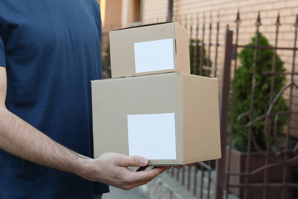 Delivery man hold blank boxes outdoor, space for text - 写真・画像