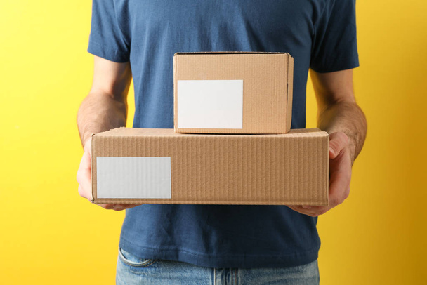 Delivery man hold blank boxes against yellow background, space f - Φωτογραφία, εικόνα