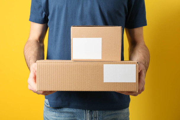 Delivery man hold blank boxes against yellow background, space f - Φωτογραφία, εικόνα