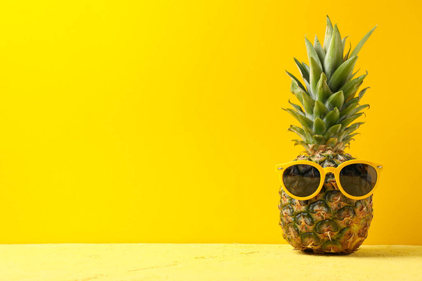 Ananas w okularach przeciwsłonecznych na żółtym tle, miejsce na tekst.  - Zdjęcie, obraz