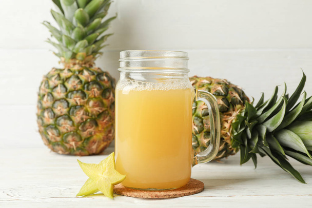 Glass jar with juice and pineapples on white wooden background,  - Photo, Image