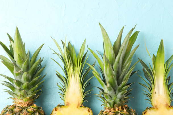 Top of pineapples on blue background, close up. Juicy fruit - Foto, Imagen