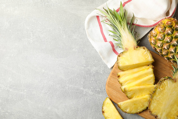 Cutting board with pineapples on grey background, top view - Foto, Bild