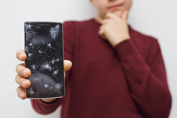 Un homme tenant un portable après un accident. Téléphone numérique avec écran cassé
. - Photo, image