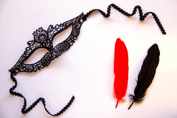 Musta pitsi karnevaali naamio naisille, punainen ja musta höyhenet valkoisella pohjalla. Litteä pano. Kopioi tila
. - Valokuva, kuva