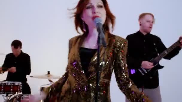 A musical band of four people playing song in the bright studio - filming a dynamic music video - ginger attractive woman singing - Footage, Video