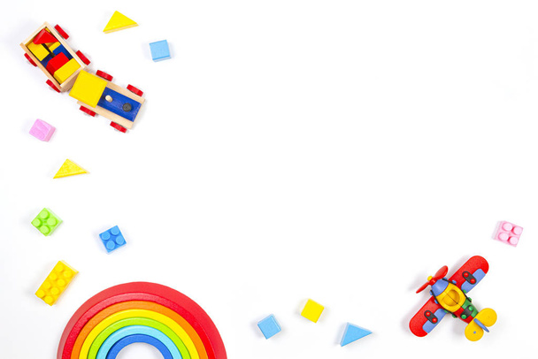 Bebek çocukların oyuncak geçmişi. Tahta tren, inşaat uçağı, oyuncak gökkuşağı, uçak ve beyaz arka planda renkli bloklar. Üst manzara, düz uzanma - Fotoğraf, Görsel