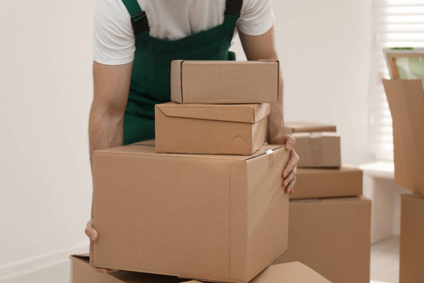 Man with cardboard boxes in room, closeup. Moving service - Foto, Imagen