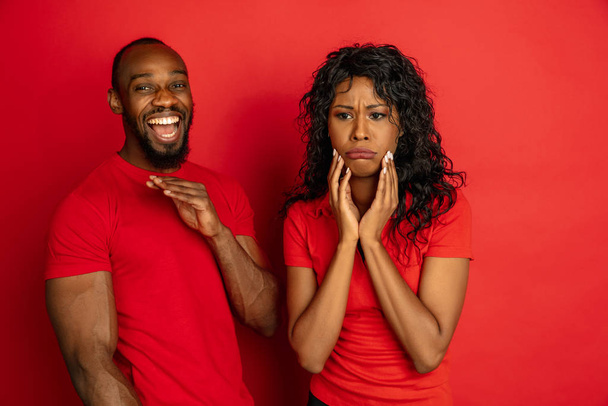 Jonge emotionele Afrikaans-Amerikaanse man en vrouw op rode achtergrond - Foto, afbeelding