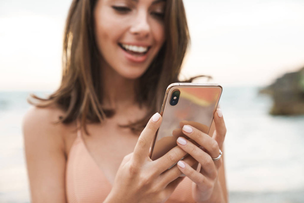 Image of nice cheerful woman smiling and using cellphone - Φωτογραφία, εικόνα