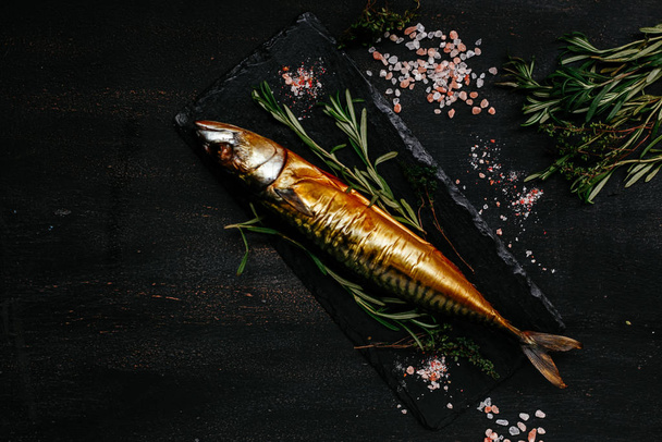 Smoked mackerel on a black plate - Valokuva, kuva