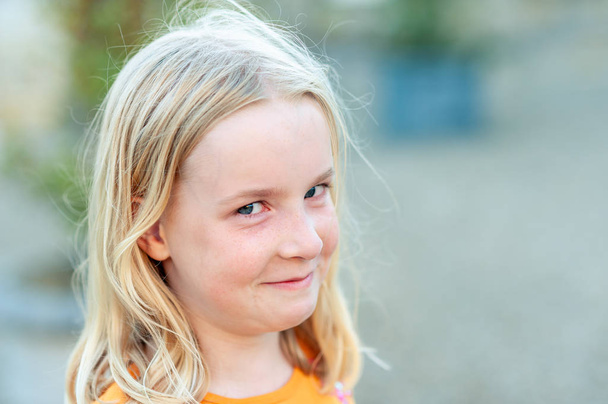 Close up headshot of a young, pretty blonde girl looking at the camera and trying not to laugh - Fotoğraf, Görsel