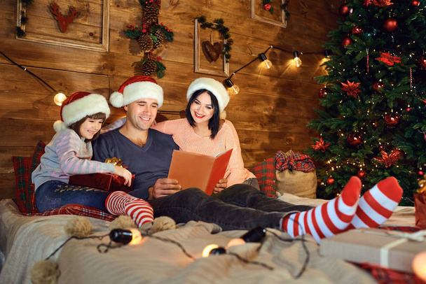 Family is reading a book in a room in Christmas. - Zdjęcie, obraz