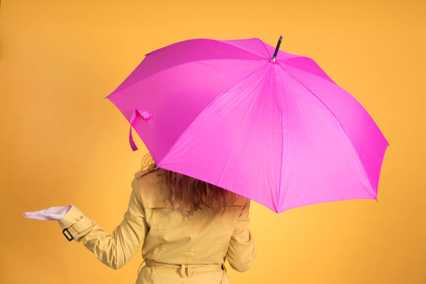 mujer de espaldas con paraguas y gabardina aislada en fondo de color - Fotó, kép