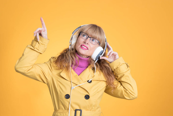 mulher adulta com fones de ouvido dançando no fundo de cor
 - Foto, Imagem