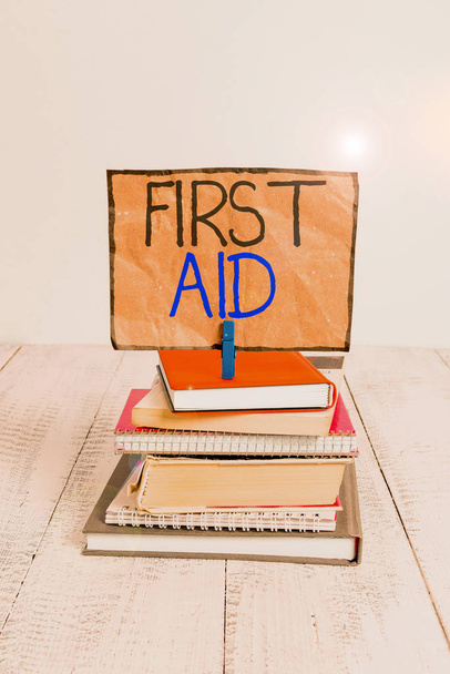 Conceptual hand writing showing First Aid. Business photo text Practise of healing small cuts that no need for medical training pile stacked books notebook pin color reminder white wooden. - Fotoğraf, Görsel