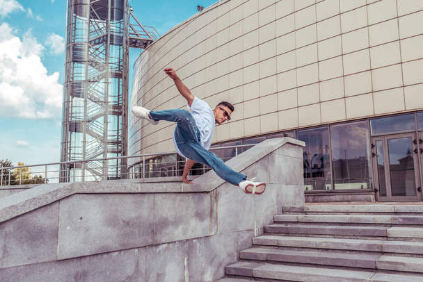Male athlete, runs and jumps in jump, summer city, hip hop style, break dancer. Free space for motivation text. Active youth lifestyle, modern fashionable hipster, street dancer. Fitness movement. - 写真・画像