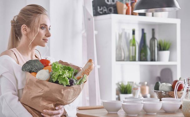 Mujer joven sosteniendo bolsa de la compra de comestibles con verduras Standi
 - Foto, imagen