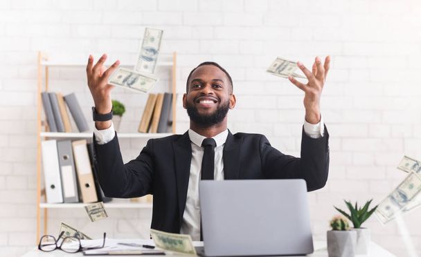 Onnellinen nuori liikemies puvussa heittää rahaa työpaikalla
 - Valokuva, kuva